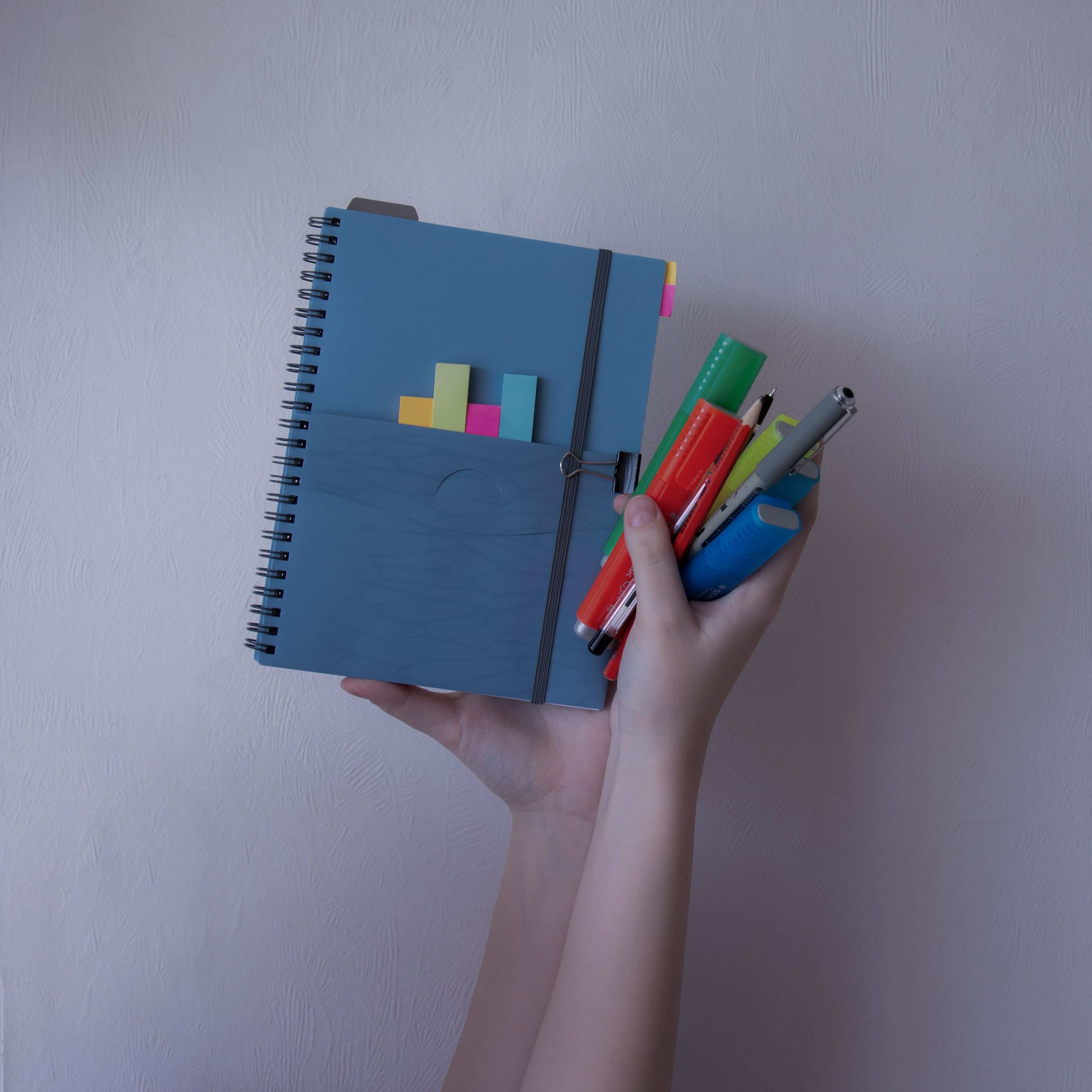 Desk workspace with paper notes and writing tools, colorful pens and sticky notes on a notebook